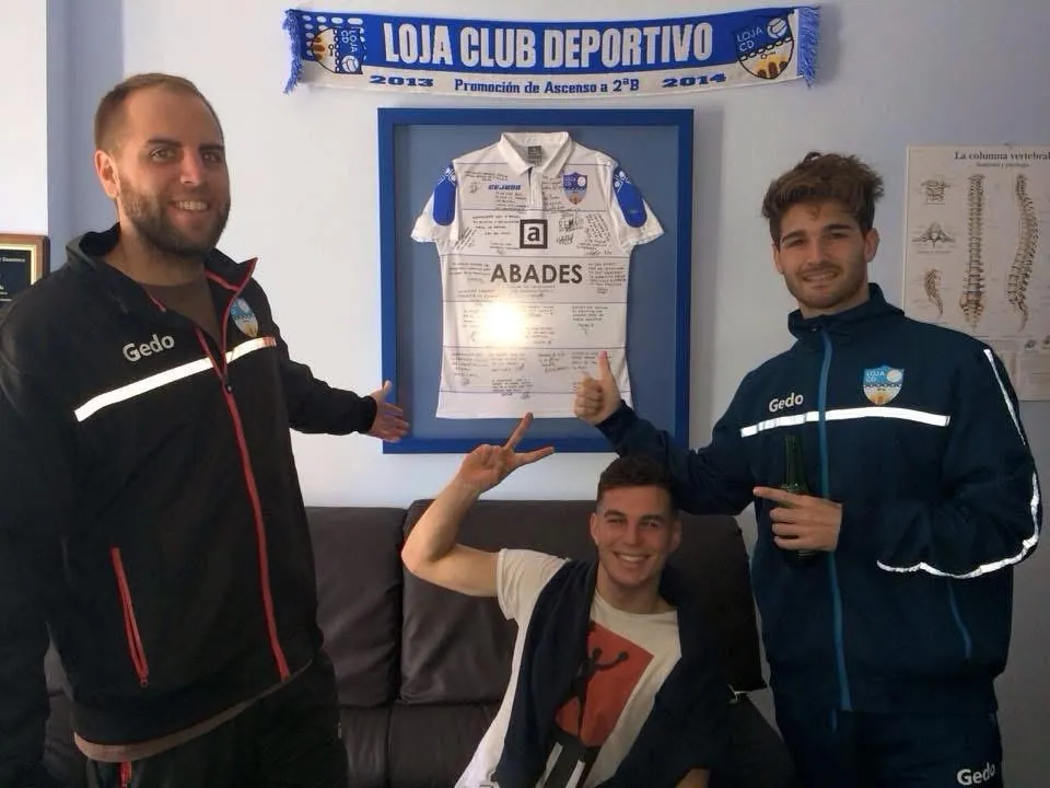 El Dr. Ryan Cevola con jugadores del CD Loja junto a una camiseta firmada de la temporada 2013-2014