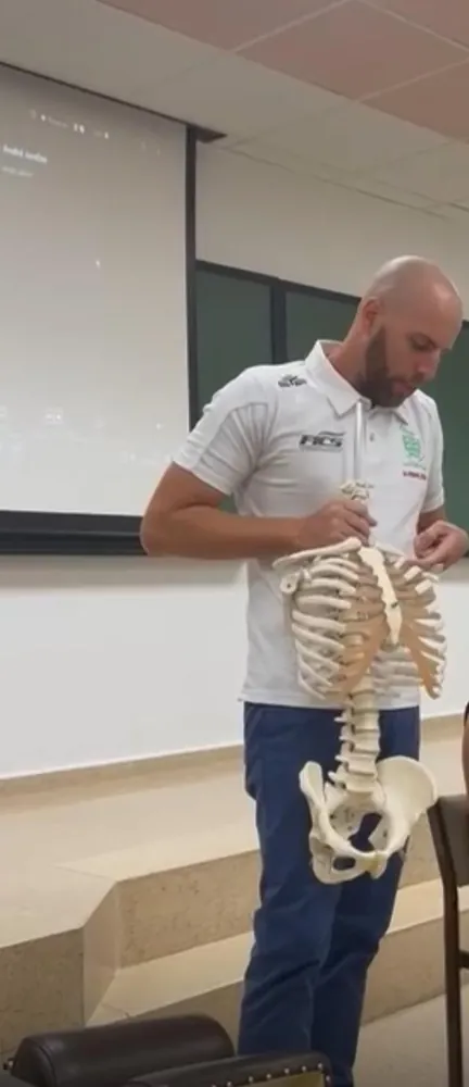 El Dr. Ryan Cevola explica la columna vertebral con un modelo anatómico durante una charla