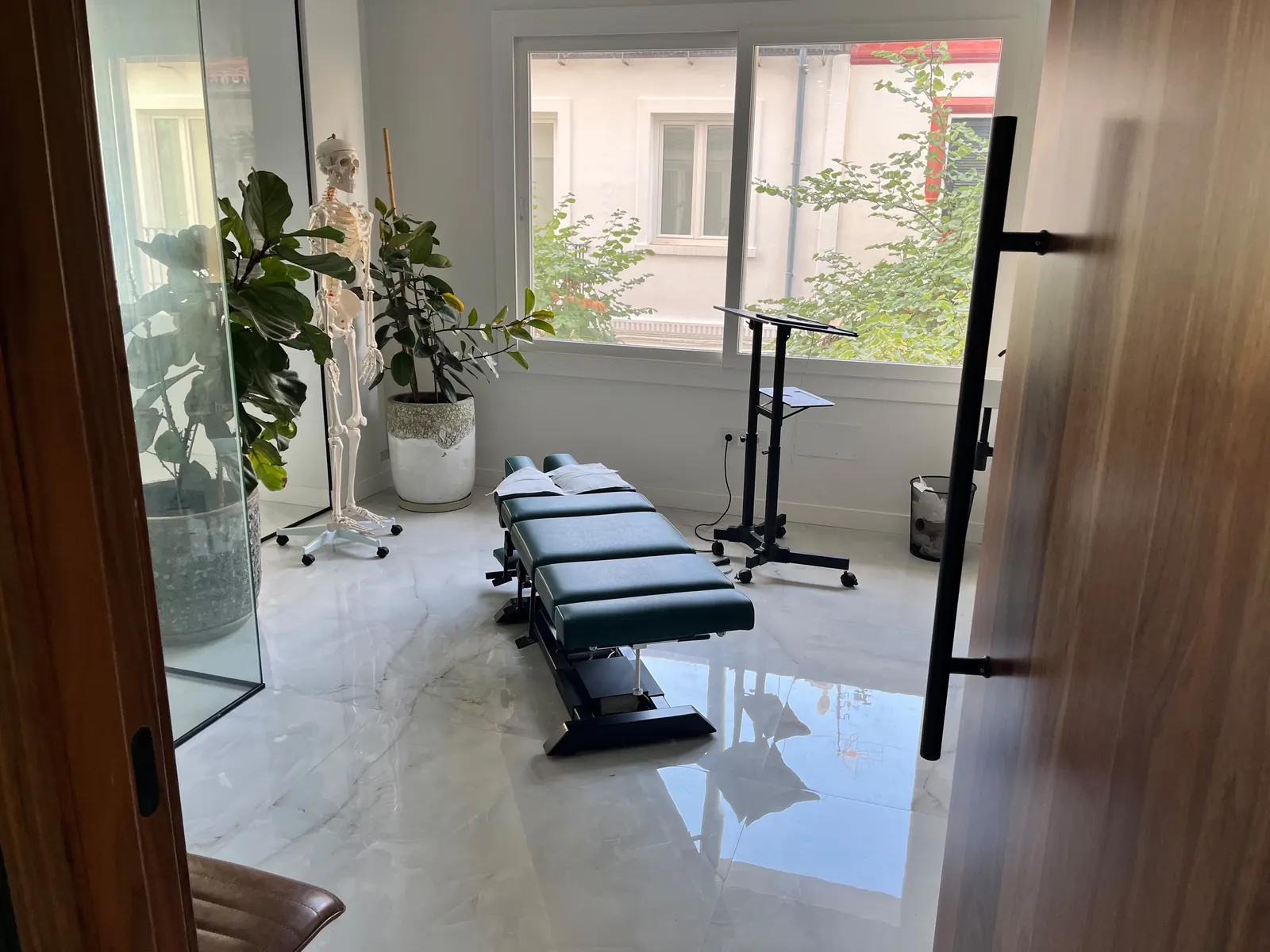 Sala de tratamiento de la consulta de Fuengirola, con camilla quiropráctica junto a la ventana
